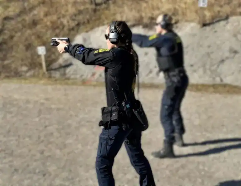 Personer i politiuniform gennemfører taktisk skydeøvelse på udendørs træningsbane